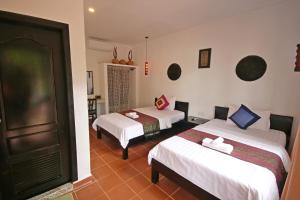 una camera d'albergo con due letti e una porta di Green Life Cottage a Siem Reap
