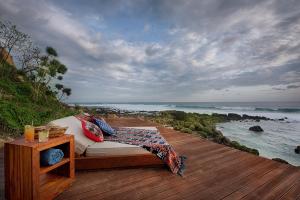 a bed on a wooden deck with a view of the ocean at Lelewatu Resort Sumba in Watukarere