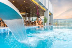 two women in bathing suits sitting in a swimming pool at Grand Gold Hotel in Danang