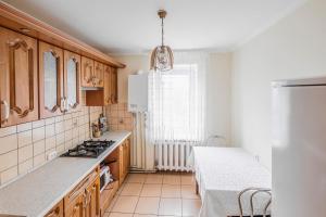 a kitchen with wooden cabinets and a stove top oven at Затишна квартира біля Льодограю in Bohuslav