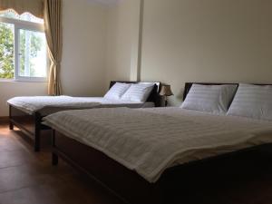 two twin beds in a room with a window at Dang Duy Hotel in Lagi