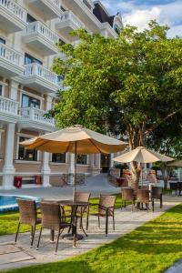 einen Tisch und Stühle mit Sonnenschirmen vor einem Gebäude in der Unterkunft Orbit Hotel in Nha Trang