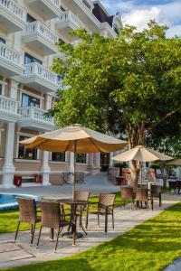 a table and chairs with umbrellas in front of a building at Orbit Hotel in Nha Trang