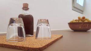 a counter with two glass bottles and a bowl of fruit at Paralos Lodging in Schinoussa +45 photos