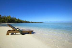 a wooden bench sitting on a beach near the water at Pacific Resort Aitutaki in Arutanga