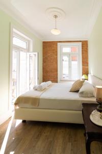 Un dormitorio con una cama grande y dos ventanas. en 1898 Home & Suites, en Lisboa