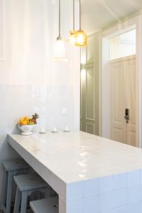 リスボンにある1898 Home & Suitesの白いキッチン(大きな白いカウンター、スツール付)