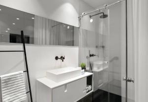 La salle de bains blanche est pourvue d'un lavabo et d'une douche. dans l'établissement The Victorian Bay Window by HolyGuest, à Tel Aviv