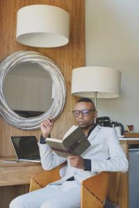 a man in a white suit reading a book at Menlyn Boutique Hotel in Pretoria