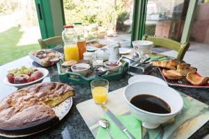 einen Tisch mit einem Frühstück mit Brot, Kaffee und Orangensaft in der Unterkunft Chambres d'Hôtes du Chalet de Caharet in Pipriac