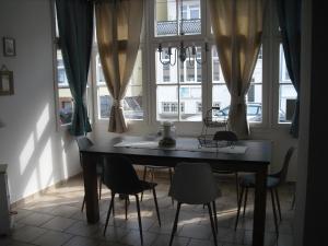a dining room table and chairs in a room with windows at Warnemünder Strandfieber in Rostock