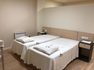 two beds in a room with white sheets at Apartamentos Villava Pamplona in Villava