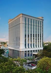 a tall white building with a lot of windows at Ramada Plaza Chennai in Chennai