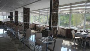 a dining room with tables and chairs and windows at Oz Cavusoglu Hotel in Bitlis