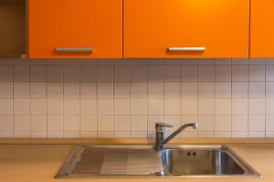 een wastafel in een keuken met oranje kasten bij San Rocco Flexyrent - Parking - WiFi - Aircon in Rapallo +68 foto's