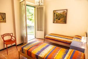 een slaapkamer met twee bedden en een stoel en een raam bij San Rocco Flexyrent - Parking - WiFi - Aircon in Rapallo