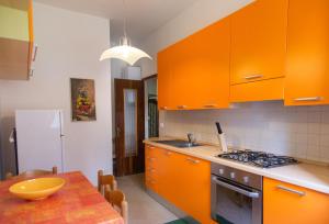 een keuken met oranje kasten en een houten tafel bij San Rocco Flexyrent - Parking - WiFi - Aircon in Rapallo