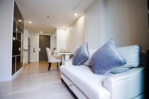 a living room with a couch with blue pillows on it at Hope Land Hotel Sukhumvit 8 in Bangkok