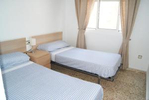 two beds in a small room with a window at Playa Delicias in Águilas