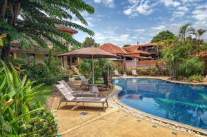 a pool with chairs and an umbrella next to a house at Temple Gardens in Bophut