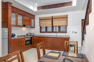 a kitchen with wooden cabinets and a table with chairs at Temple Gardens in Bophut 