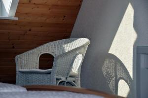 una silla de mimbre con una sombra en la pared en Pension am See, en Schluchsee