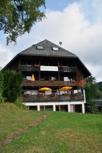 un edificio con mesas y sombrillas delante en Pension am See en Schluchsee