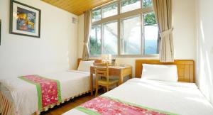a bedroom with two beds and a table and a window at Red Brick Villas in Nanzhuang