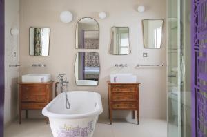 a bathroom with a tub and a sink and mirrors at Hôtel Crayon in Paris