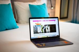 un ordinateur portable assis au-dessus d'un lit dans l'établissement Hôtel Le Bord'O Vieux Port, à La Rochelle