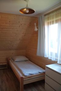 a small bed in a room with a window at Całoroczne Domki Nad Zatoką in Polańczyk