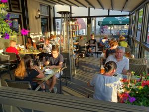 un groupe de personnes assises à table dans un restaurant dans l'établissement Hotel Café Restaurant "De Kroon", à Wissenkerke