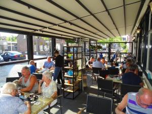 un groupe de personnes assises à table dans un restaurant dans l'établissement Hotel Café Restaurant "De Kroon", à Wissenkerke