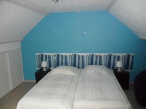 a bedroom with a large bed with a blue wall at le gite d'olhain in Fresnicourt-le-Dolmen