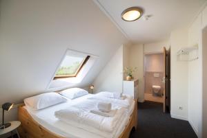a bedroom with a bed with white sheets and a window at Rufus aan het water in Broek