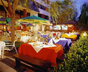 a restaurant with tables and chairs and umbrellas at CITIC Hotel Beijing Airport in Shunyi