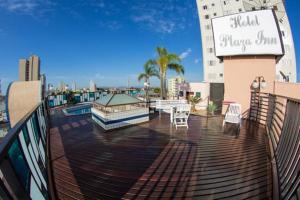 a deck with tables and chairs on a building at Hotel Plaza Inn Flat Residence in Alfenas