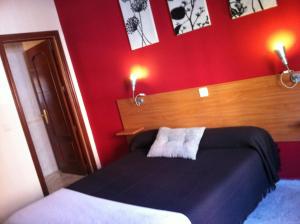 um quarto com uma cama e uma parede vermelha em Hostal Neptuno em Cáceres