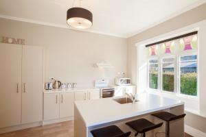 een keuken met witte kasten, een wastafel en 2 ramen bij Kingston Villa in Kingston