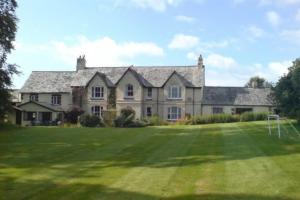 uma casa grande com um grande campo de relva em frente em Coach House Cottage em Merton