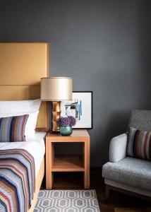 a bedroom with a bed with a lamp and a chair at AMERON Köln Hotel Regent in Cologne
