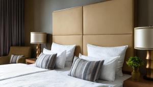 una camera d'albergo con letto con lenzuola e cuscini bianchi di AMERON Köln Hotel Regent a Colonia