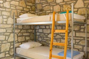 two bunk beds in a room with a stone wall at Himara Hostel in Himare