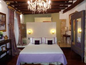 ein Schlafzimmer mit einem großen Bett mit einem Kronleuchter in der Unterkunft Hotel Boutique Nueve Leyendas in Úbeda