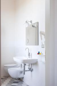La salle de bains blanche est pourvue d'un lavabo et de toilettes. dans l'établissement Gianburrasca, à Florence