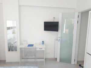 Cette chambre blanche dispose d'un bureau et d'une télévision murale. dans l'établissement Appartamento "Un Bacio sul Mare", à Laigueglia