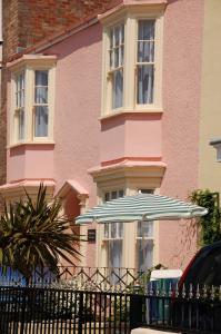 a pink house with an umbrella in front of it at Woodbine Cottage in Tenby