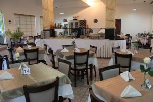 a dining room with tables and chairs with white table runners at Marruá Hotel in Bonito