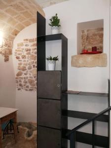 ein schwarzer Schrank mit zwei Topfpflanzen an einer Wand in der Unterkunft L' Edera in Fasano