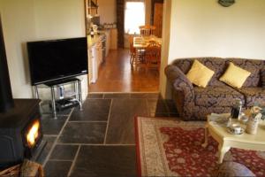 a living room with a couch and a television at Coach House Cottage in Merton